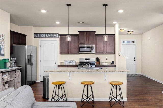 kitchen featuring a sink, a breakfast bar, appliances with stainless steel finishes, dark wood-type flooring, and dark brown cabinets