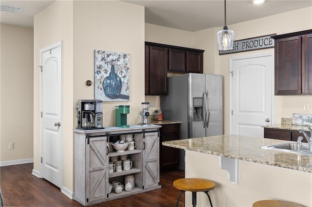 kitchen featuring visible vents, a breakfast bar area, stainless steel fridge, and dark brown cabinets