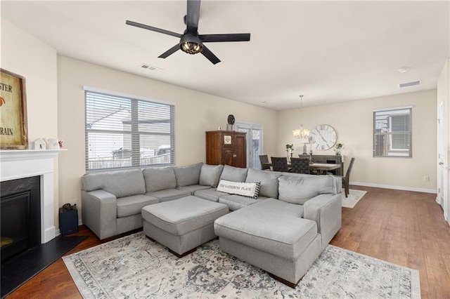 living room with wood finished floors, a glass covered fireplace, baseboards, and visible vents