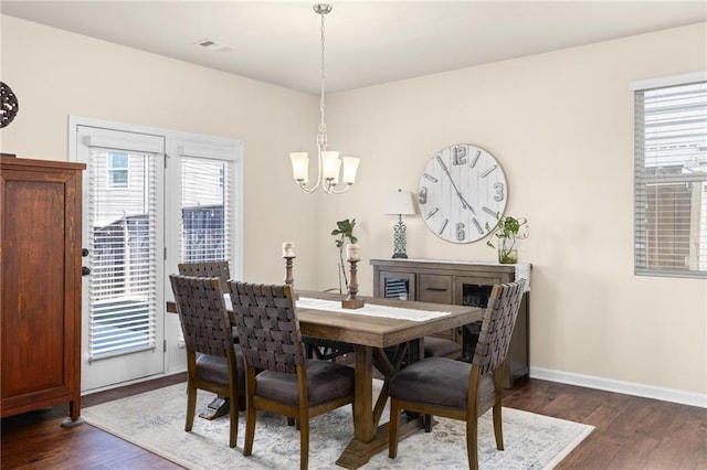 dining area with baseboards, visible vents, wood finished floors, and a chandelier