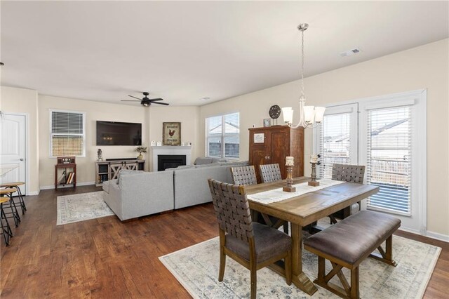 dining room with dark wood-style floors, visible vents, baseboards, and ceiling fan with notable chandelier