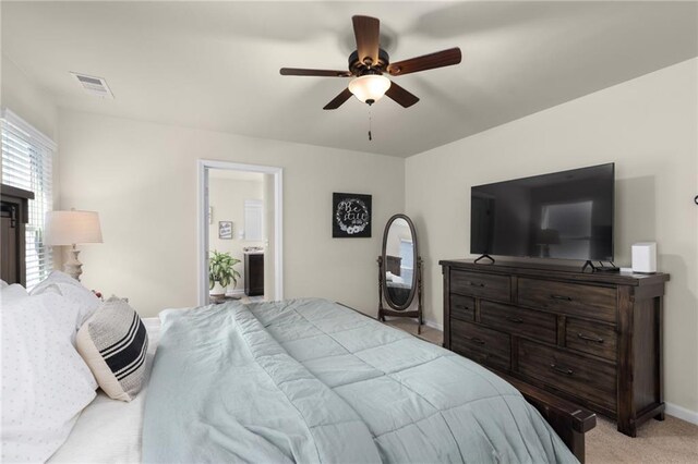 carpeted bedroom with ensuite bathroom, baseboards, and ceiling fan