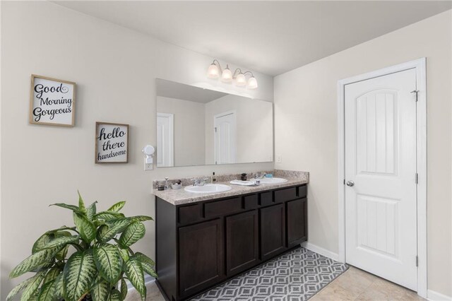 bathroom featuring double vanity, baseboards, and a sink