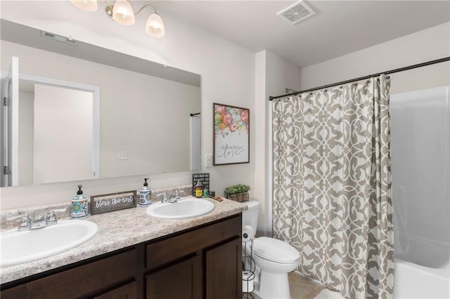 bathroom featuring double vanity, visible vents, toilet, and a sink