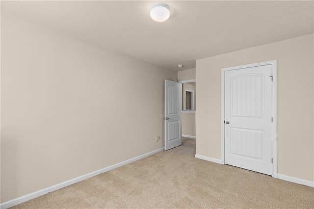 unfurnished bedroom featuring light colored carpet and baseboards