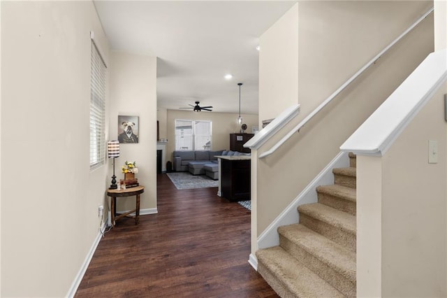 interior space with a ceiling fan, baseboards, stairs, and wood finished floors