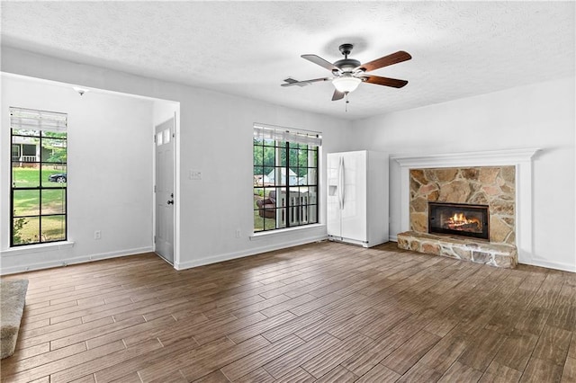 2568 Redfield Dr, Norcross, GA 30071 - unfurnished living room featuring a textured ceiling, a ceiling fan, wood finished floors, plenty of natural light, and a fireplace