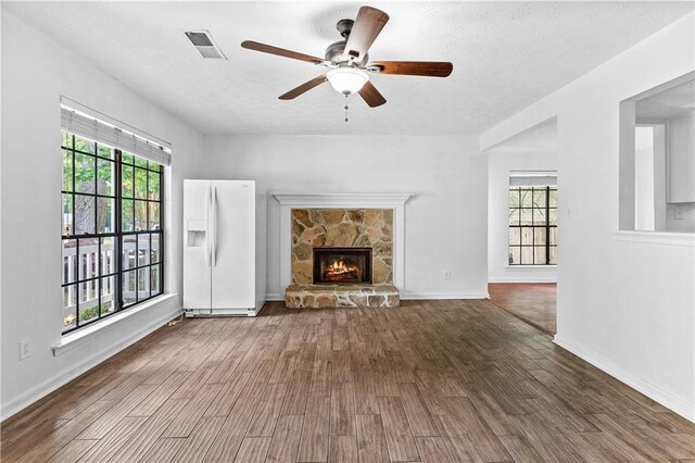 2568 Redfield Dr, Norcross, GA 30071 - unfurnished living room featuring healthy amount of natural light, wood finished floors, ceiling fan, a fireplace, and a textured ceiling