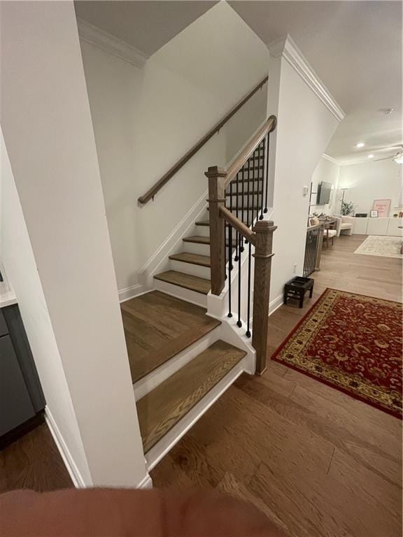 stairway with hardwood / wood-style floors, ceiling fan, and crown molding