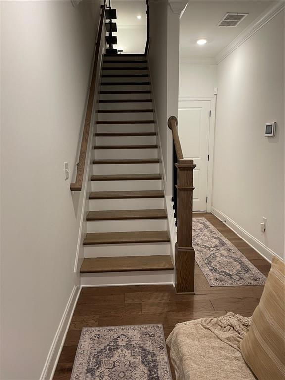 stairs with hardwood / wood-style floors and ornamental molding