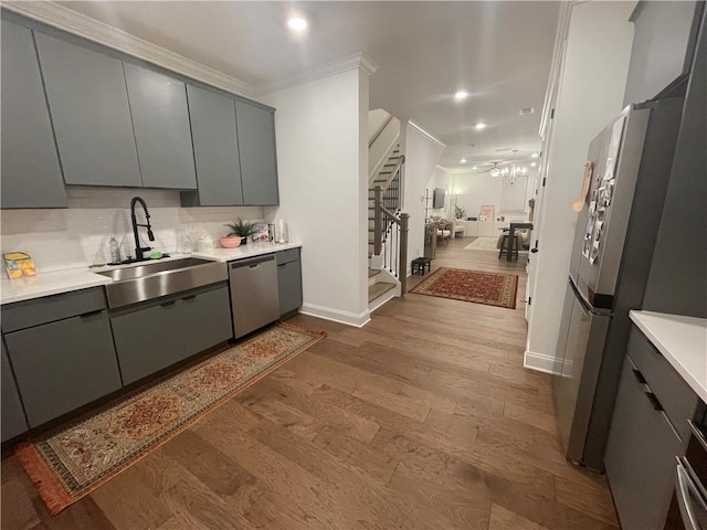 kitchen featuring sink, tasteful backsplash, crown molding, appliances with stainless steel finishes, and light wood-type flooring