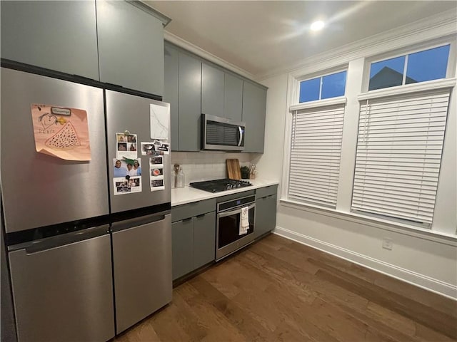 kitchen featuring decorative backsplash, gray cabinetry, stainless steel appliances, crown molding, and dark hardwood / wood-style floors