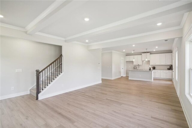 unfurnished living room with beam ceiling, stairway, light wood-style flooring, recessed lighting, and ornamental molding
