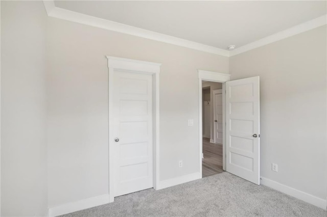 unfurnished bedroom featuring carpet, baseboards, and ornamental molding