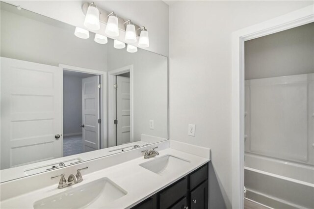 full bathroom with double vanity, baseboards, and tub / shower combination