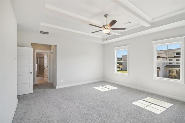 carpeted spare room with a tray ceiling, ceiling fan, and baseboards