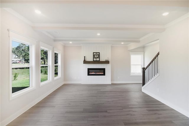 unfurnished living room with healthy amount of natural light, wood finished floors, stairway, crown molding, and beamed ceiling