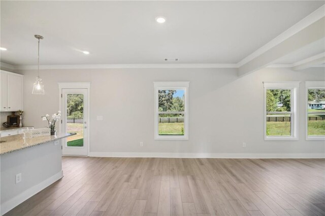 kitchen with white cabinets, crown molding, plenty of natural light, light wood-style floors, and open floor plan