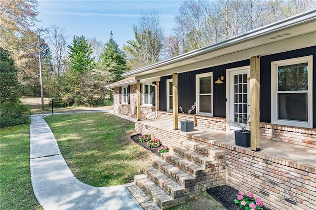 exterior space with a lawn, covered porch, and brick siding