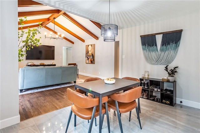 dining area with baseboards, lofted ceiling with beams, and a chandelier