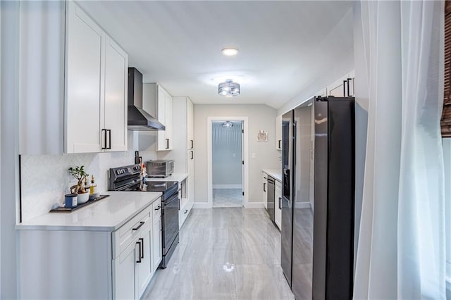 kitchen featuring light countertops, black electric range oven, wall chimney exhaust hood, baseboards, and refrigerator with ice dispenser