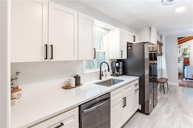 kitchen with a sink, light countertops, stainless steel appliances, white cabinetry, and decorative backsplash