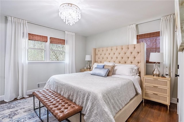 bedroom featuring visible vents, baseboards, wood finished floors, and a notable chandelier