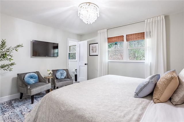 bedroom featuring baseboards, a chandelier, and multiple windows