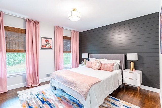 bedroom featuring visible vents, baseboards, wood finished floors, and multiple windows