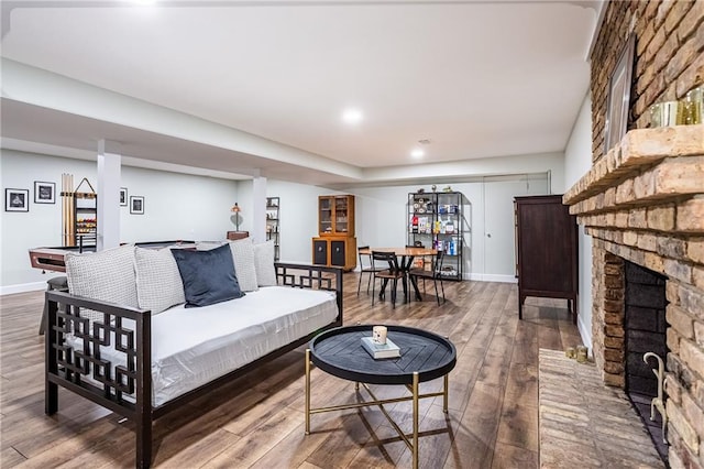 living area with baseboards, a fireplace, and wood finished floors