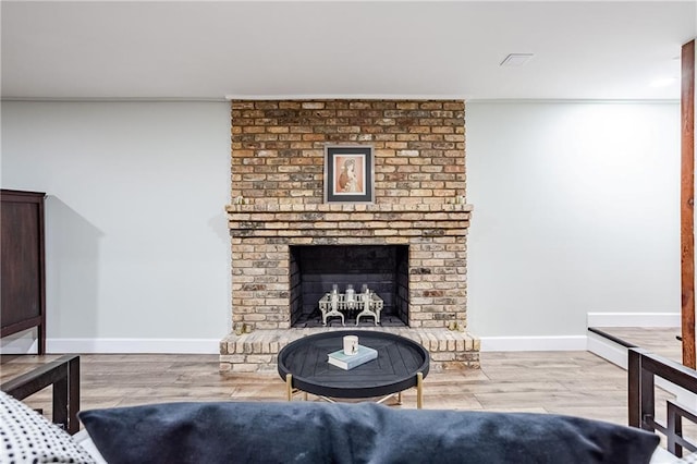 living room featuring crown molding, baseboards, a brick fireplace, and wood finished floors