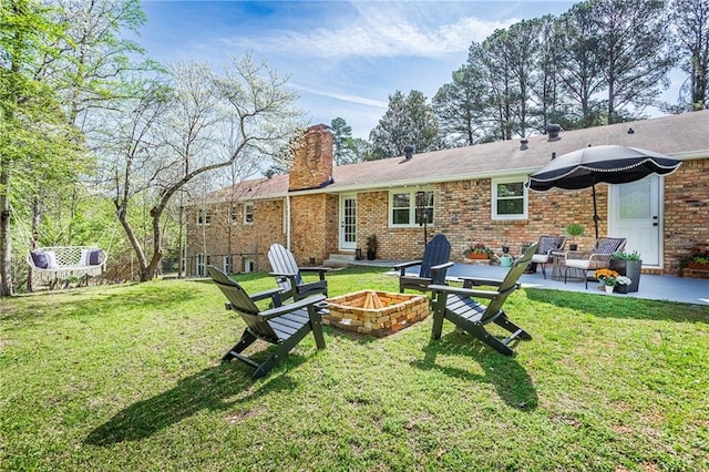 back of property with a lawn, a fire pit, a patio area, and a chimney