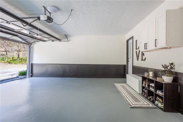 garage featuring a garage door opener and a wainscoted wall