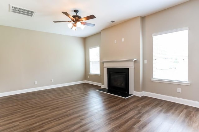 unfurnished living room featuring ceiling fan, dark hardwood / wood-style floors, and plenty of natural light