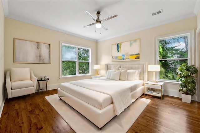 bedroom featuring ceiling fan, dark wood-type flooring, visible vents, baseboards, and crown molding