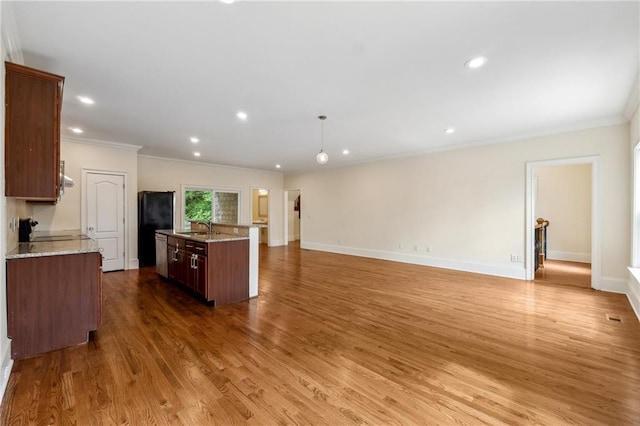 kitchen featuring crown molding, a kitchen island with sink, a sink, wood finished floors, and baseboards