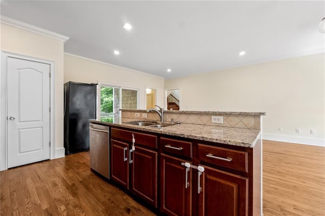 kitchen with a sink, freestanding refrigerator, reddish brown cabinets, dishwasher, and tasteful backsplash