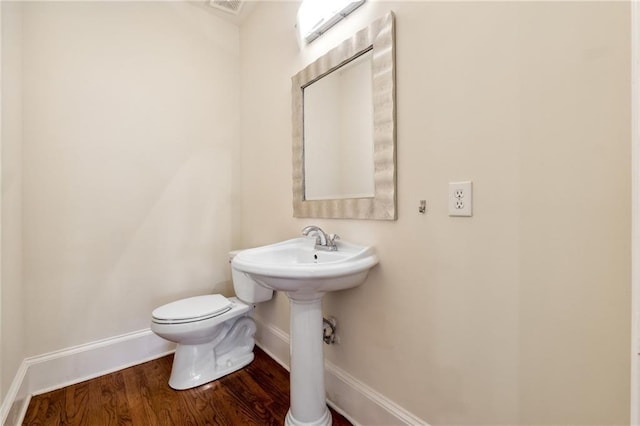 half bath featuring toilet, baseboards, and wood finished floors