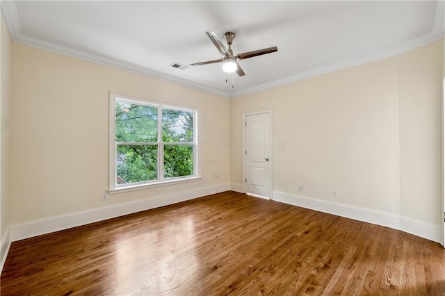 spare room featuring baseboards, visible vents, a ceiling fan, wood finished floors, and crown molding