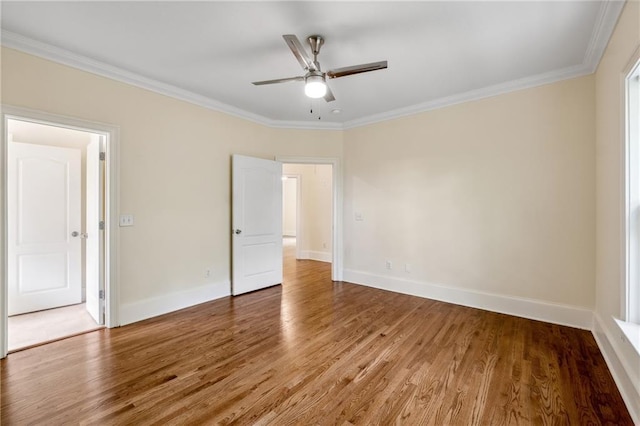 spare room with a ceiling fan, crown molding, baseboards, and wood finished floors