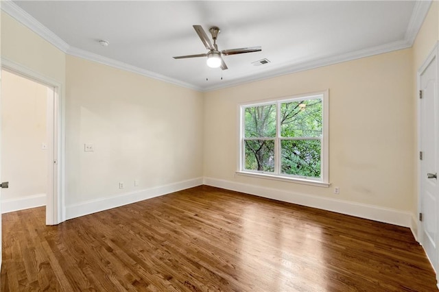 spare room featuring visible vents, ornamental molding, ceiling fan, wood finished floors, and baseboards