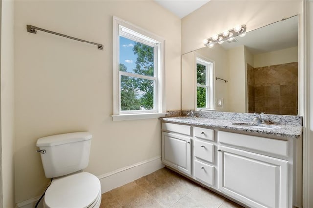 full bath featuring toilet, double vanity, baseboards, and a sink