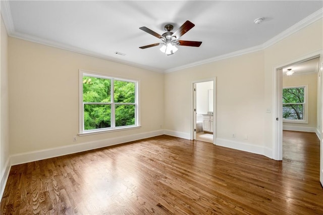 unfurnished room with baseboards, wood finished floors, a wealth of natural light, and crown molding