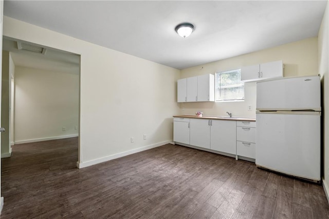 kitchen with baseboards, dark wood-style floors, freestanding refrigerator, white cabinetry, and a sink