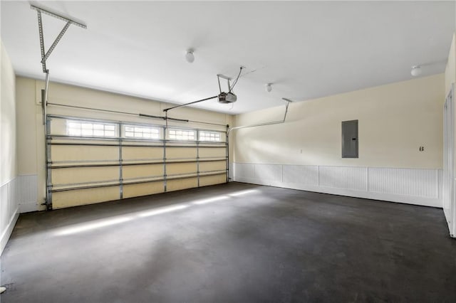 garage featuring a wainscoted wall, electric panel, and a garage door opener