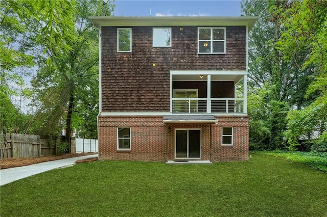 back of house featuring fence, a lawn, and brick siding