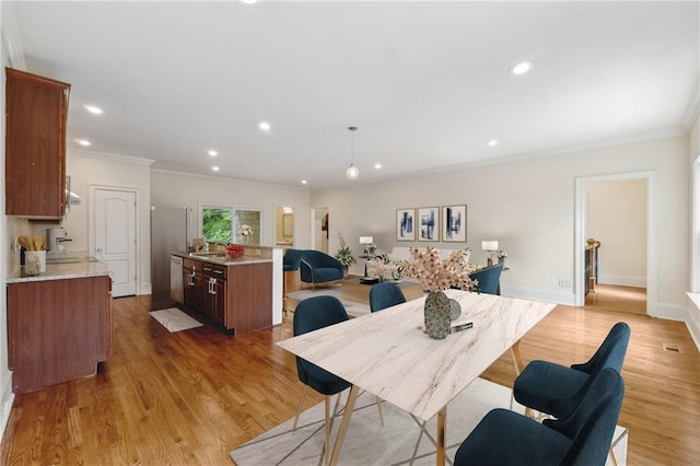 dining space featuring crown molding, light wood finished floors, and recessed lighting