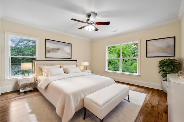 bedroom featuring visible vents, crown molding, baseboards, and wood finished floors