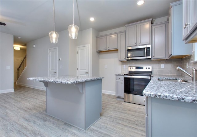 119 Greenview Ct Unit 1303, Homer, GA 30547 - kitchen featuring stainless steel appliances, light wood-style flooring, light stone countertops, decorative backsplash, and a kitchen breakfast bar