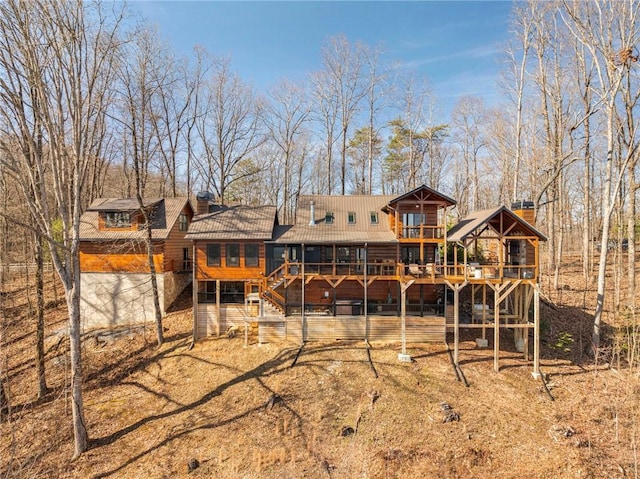 rear view of house featuring a deck, stairs, and a chimney